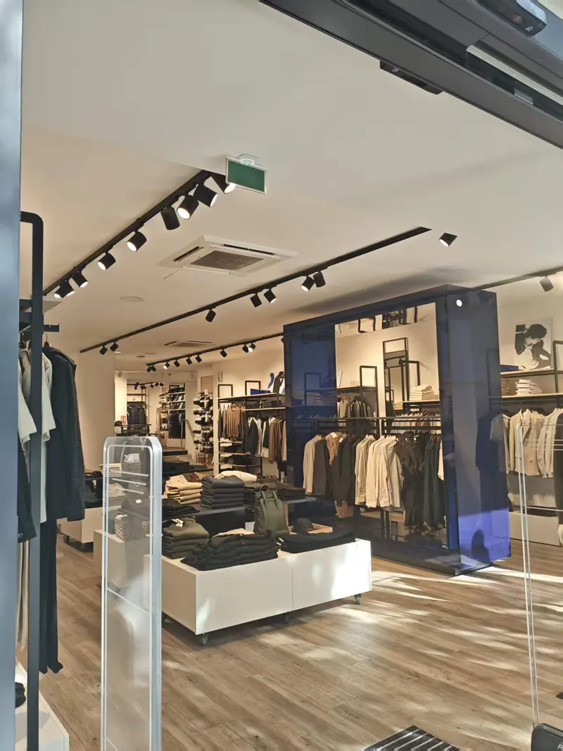 Black track and cylindrical spotlights on a white ceiling in a minimalist apparel store